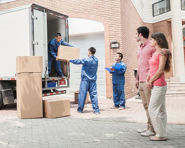 Couple watching moving workers loading boxes into moving truck to take them to their destination